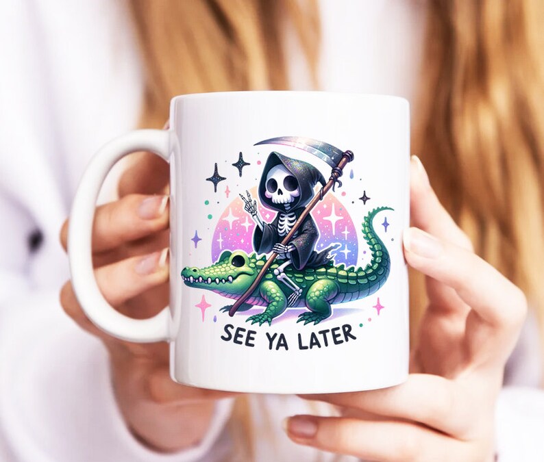 May include: White ceramic mug with a colorful graphic of a skeleton riding a green alligator. The skeleton is wearing a black hooded robe and holding a scythe. The text "See Ya Later" is printed below the graphic.