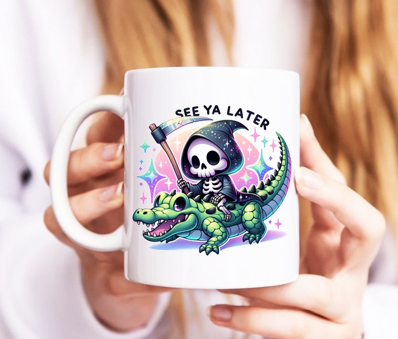 Pu&ograve; includere: Tazza in ceramica bianca con un'immagine di cartone animato nero e verde della Morte che cavalca un alligatore verde. Il testo "See Ya Later" &egrave; stampato in nero sopra l'immagine.