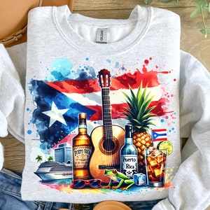 Puede incluir: Una ilustraci&oacute;n de acuarela de una bandera puertorrique&ntilde;a con una guitarra, una pi&ntilde;a, ron, un vaso de ron y cola, gafas de sol y una rana verde. El texto "Puerto Rico" est&aacute; en la botella de ron.
