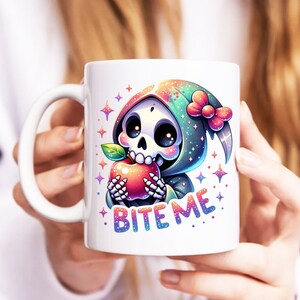 May include: White ceramic mug with a colorful illustration of a cartoon skeleton wearing a green hooded robe and holding a red apple. The text "Bite Me" is printed on the mug.