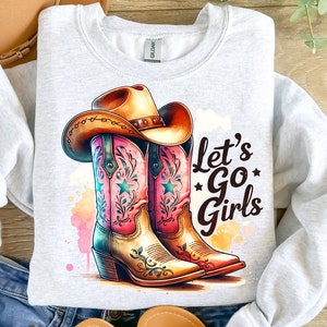 Op de afbeelding: Een lichtgrijs sweatshirt met een aquarelontwerp van een cowboyhoed en -laarzen. De laarzen zijn roze en turquoise met ster- en bloemaccenten. De tekst "Let's Go Girls" is in het zwart gedrukt.