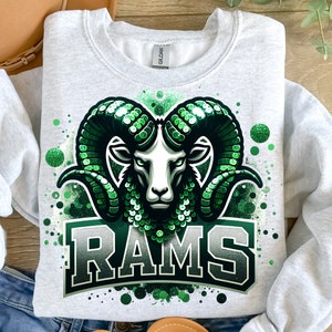 May include: A gray sweatshirt with a green and white ram's head graphic and the word "RAMS" in green letters. The graphic has a sparkly, sequined effect.