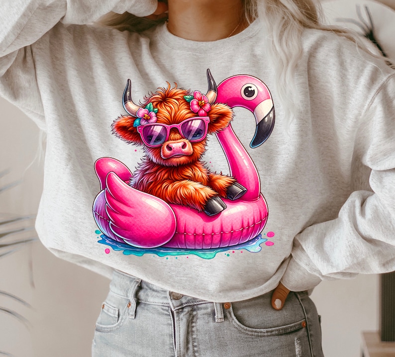 May include: A gray sweatshirt with a cartoon illustration of a Highland cow wearing sunglasses and riding a pink flamingo pool float. The cow has a flower crown on its head.