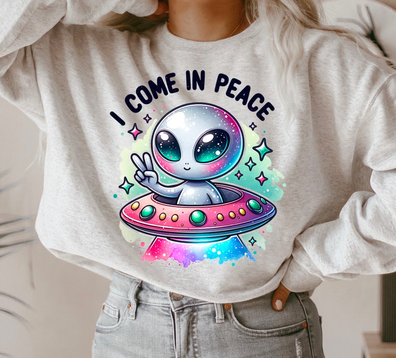 May include: A gray sweatshirt with a cartoon alien in a spaceship. The alien is waving with a peace sign and the text "I come in peace" is above the spaceship.