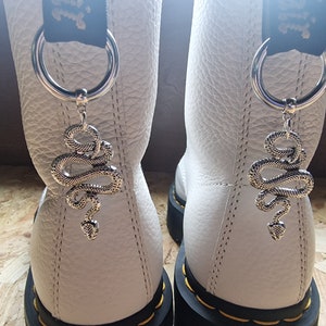 May include: White leather boots with black laces and silver snake charms attached to the laces.