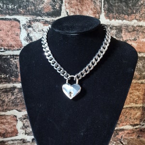 May include: A silver chain choker necklace with a heart-shaped padlock pendant.