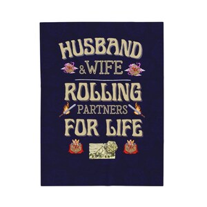 Op de afbeelding: Een marineblauwe achtergrond met de tekst "Husband & Wife Rolling Partners For Life" in een gouden lettertype. De tekst wordt omringd door afbeeldingen van dobbelstenen, zwaarden en kronen.