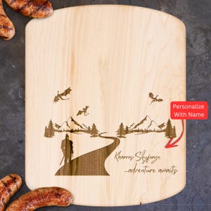 May include: A wooden cutting board with a personalized inscription that reads "Kharros Skyforge...adventure awaits". The board features a design of a figure standing on a path leading through a mountain landscape with dragons flying overhead.