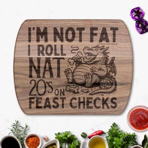 Puede incluir: Una tabla de cortar de madera con bordes redondeados presenta el texto "I'M NOT FAT I ROLL NAT 20S ON FEAST CHECKS" y una ilustración de un dragón de dibujos animados. Dos dados morados son visibles en el fondo. La tabla está rodeada de ingredientes.
