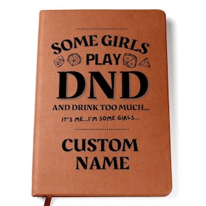 Puede incluir: Un diario de cuero marrón con el texto "Some girls play DND and drink too much... It's me... I'm some girls..." y "Custom Name" en letras negras.