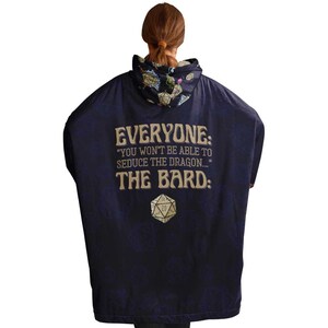 Op de afbeelding: Een marineblauwe poncho met capuchon met een gouden print die luidt: "Iedereen: "Je zult de draak niet kunnen verleiden..." De bard:" en een grafische afbeelding van een 20-zijdige dobbelsteen.