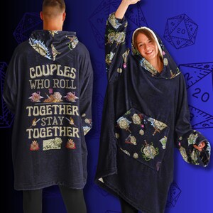 Op de afbeelding: Een marineblauwe hoodie-deken met een dobbelsteenpatroon en de tekst "Couples who roll together stay together".