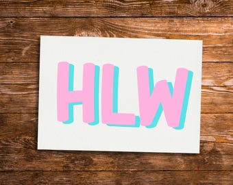 May include: A white rectangular card with the letters "HLW" in pink, with a light blue shadow effect. The card is set against a dark brown wooden background.