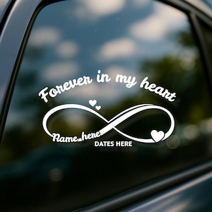 May include: White car decal with the text "Forever in my heart" above an infinity symbol. The infinity symbol has a heart on the right side and two small hearts above it. The decal includes space for a name and dates.