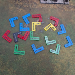Op de afbeelding: Een verzameling kleurrijke, L-vormige spelstukken met verschillende woorden erop gedrukt, waaronder "Frozen" en "Disorder". De stukken zijn in blauw, rood, groen en geel en liggen op een getextureerd oppervlak.