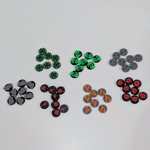 May include: A collection of 10 different colored plastic game tokens. The tokens are round and have various symbols on them. The tokens are arranged in groups of 10 on a white surface.