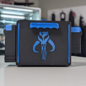 May include: A black storage box with blue trim and a blue Mandalorian symbol on the front. The box has two side compartments.
