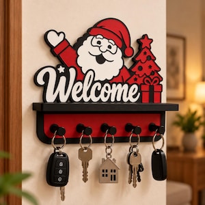 May include: A wall-mounted key holder featuring a red and white Santa Claus graphic, a red Christmas tree, and the word Welcome in white script. The black shelf has five black hooks, each holding a set of keys, including a car fob and house key.