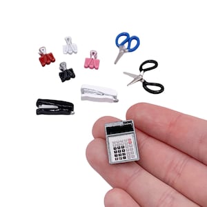 May include: A set of miniature office supplies, including a black stapler, a white stapler, a calculator, two pairs of scissors, and four binder clips in red, pink, and silver.