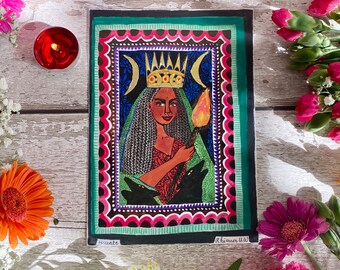 May include: A colorful illustration of a woman with a crown and a torch, surrounded by a decorative frame. The woman is holding a torch and has two black dogs at her feet. The text "Hecate" and "Rhiannon W.W" are visible at the bottom of the image.