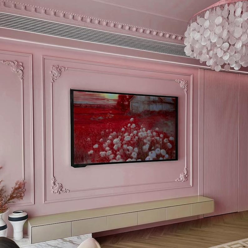 May include: A pink wall with ornate molding and a flat screen TV displaying a landscape painting. The TV is mounted above a long, white entertainment console with drawers.