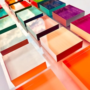 May include: A collection of colorful, square, acrylic blocks stacked on top of each other. The blocks are arranged in a staggered pattern, creating a dynamic and modern design.