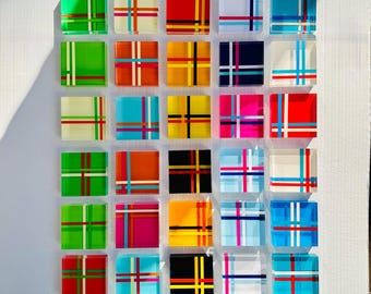 May include: A collection of 36 small square acrylic blocks with different colored plaid patterns. Each block has a different color combination of red, green, blue, yellow, white, black, and pink.