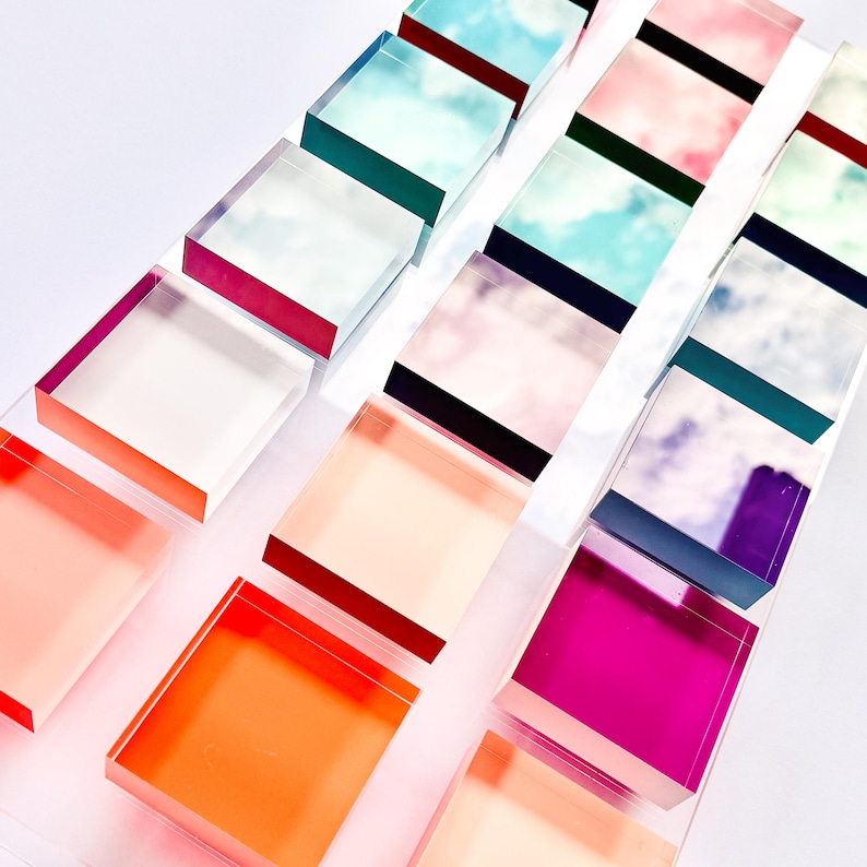 May include: A collection of colorful, translucent acrylic blocks stacked on top of each other. The blocks are arranged in a staggered pattern, creating a visually appealing display. The blocks are made of clear acrylic and have a variety of colors, including pink, blue, green, and purple.