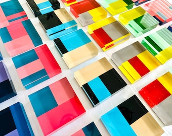 Puede incluir: Una colección de bloques de acrílico geométricos y coloridos. Cada bloque presenta una combinación única de colores y patrones, creando una exhibición visualmente estimulante.