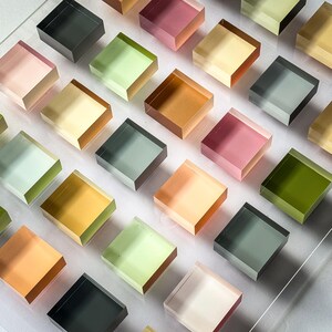 Pode incluir: Um conjunto de blocos quadrados transl&uacute;cidos em uma variedade de cores, incluindo rosa, verde, amarelo e laranja. Os blocos s&atilde;o dispostos em uma grade, criando um padr&atilde;o visualmente atraente. Os blocos parecem ser feitos de um material transparente.