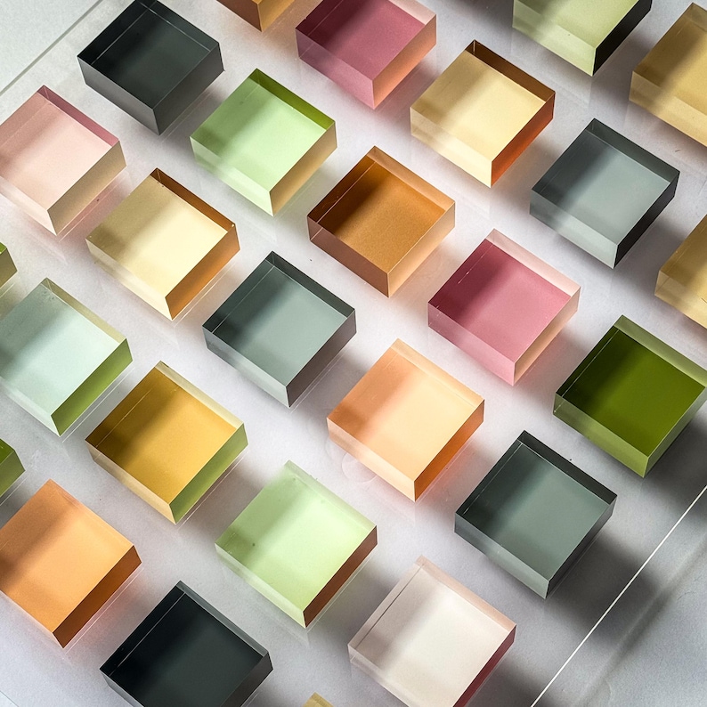 Pode incluir: Um conjunto de blocos quadrados transl&uacute;cidos em uma variedade de cores, incluindo rosa, verde, amarelo e laranja. Os blocos s&atilde;o dispostos em uma grade, criando um padr&atilde;o visualmente atraente. Os blocos parecem ser feitos de um material transparente.