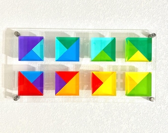 May include: A set of eight colorful geometric squares, each made of four triangles in different colors. The squares are arranged in two rows of four, with the colors alternating in a rainbow pattern.