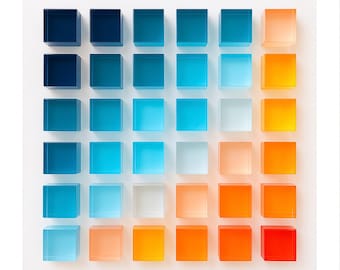Puede incluir: Una pieza de arte mural cuadrada que presenta una cuadrícula de treinta y seis cubos de acrílico translúcido dispuestos en seis filas y seis columnas. Los cubos muestran un degradado de color que va del azul marino profundo al rojo y naranja.