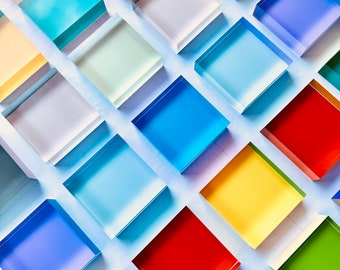 Puede incluir: Un fondo blanco con varios cuadrados de colores dispuestos en un patrón. Los cuadrados están hechos de vidrio o plástico y tienen un acabado brillante. Los colores incluyen azul, rojo, amarillo, verde y blanco.