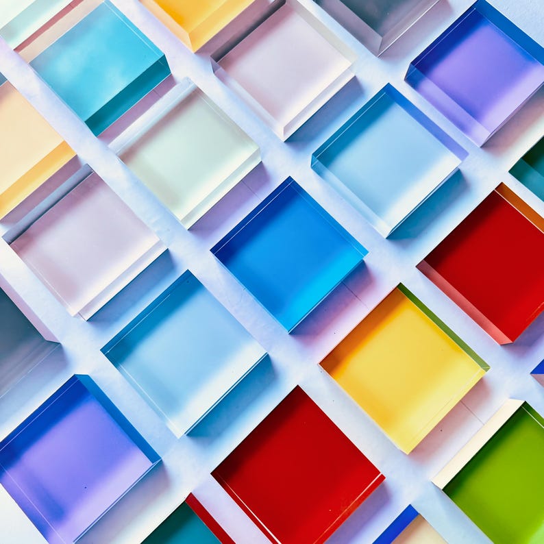 May include: A pattern of colourful, translucent square blocks in shades of blue, red, yellow, green, and purple. The blocks are arranged diagonally, creating a vibrant design. The blocks appear to be made of glass or acrylic, with a slight sheen.