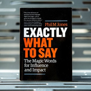 May include: A black book with the title "Exactly What To Say: The Magic Words for Influence and Impact" by Phil M Jones.