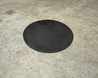 May include: A round, black metal disc. The disc is smooth and has a slightly rough texture.