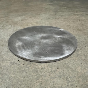 May include: A round, silver metal disc with a brushed finish.