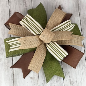 Pu&ograve; includere: Un fiocco decorativo con strati di juta e nastro nei toni del marrone, verde e beige. Il fiocco ha un nodo centrale ed &egrave; impreziosito da nastro a righe. Ideale per ghirlande e decorazioni stagionali.