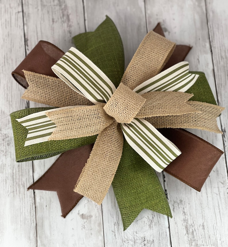 Pu&ograve; includere: Un fiocco decorativo con strati di juta e nastro nei toni del marrone, verde e beige. Il fiocco ha un nodo centrale ed &egrave; impreziosito da nastro a righe. Ideale per ghirlande e decorazioni stagionali.