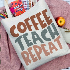 Może przedstawiać: Biała płócienna torba na zakupy z napisem "COFFEE TEACH REPEAT" w brązowych, szarych i różowych literach. Torba leży na różowej, puszystej powierzchni.