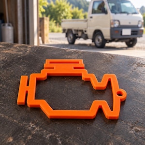Pode incluir: Um recorte plano e bidimensional de cor laranja brilhante com a forma do símbolo clássico da luz de verificação do motor. O objeto apresenta uma silhueta estilizada de um bloco de motor com um pequeno orifício circular no lado direito.