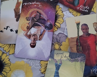 Puede incluir: Un conjunto de cartas de tarot con ilustraciones coloridas e imágenes simbólicas. Las cartas representan figuras, escenas y símbolos, incluyendo las cartas "Templanza" y "Paje de Espadas". Las cartas están dispuestas sobre una tela con estampado floral.