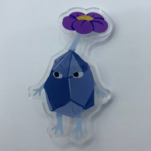 Puede incluir: Un personaje azul, parecido a un cristal, con una flor morada en la parte superior. El personaje tiene dos piernas pequeñas y dos brazos. El personaje tiene una expresión de sorpresa en su rostro.