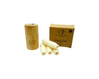 May include: An image shows a bamboo dental floss dispenser and a cardboard box of refills. The box is labelled "Tu-Untangle DENTAL FLOSS Refills" with a turtle logo. Several rolls of floss are next to the box.