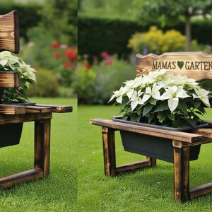 Puede incluir: Un banco r&uacute;stico de madera con tinte oscuro, que sostiene una jardinera rectangular negra llena de plantas con flores blancas. El banco tiene un respaldo con el texto "MAMA'S GARTEN" y un s&iacute;mbolo de coraz&oacute;n.