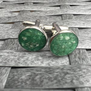 Peut inclure: Une paire de boutons de manchette en argent avec des inserts en résine mouchetée de vert et de blanc.