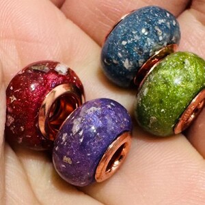 May include: Four round beads with sterling silver 18ct gold plated cores . The beads are made of a translucent material with flecks of color. The colors are red, green, blue, and purple.
