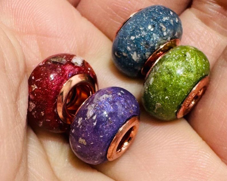 May include: Four round beads with sterling silver 18ct gold plated cores . The beads are made of a translucent material with flecks of color. The colors are red, green, blue, and purple.