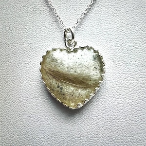 Peut inclure: Un collier avec un pendentif en forme de cœur argenté et un insert en résine transparente contenant une mèche de cheveux.